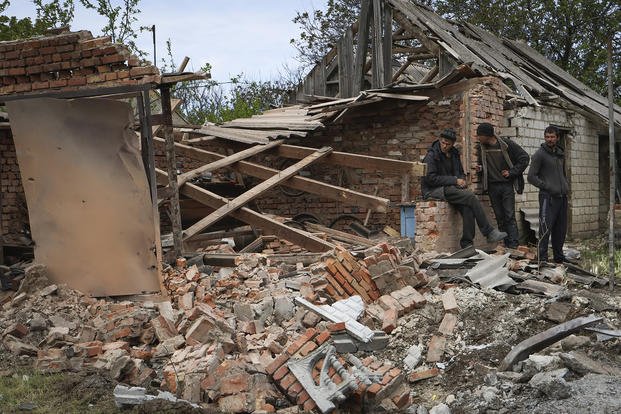 Local residents stand next to a building that was damaged overnight after Russian shelling in Komyshevakha, Zaporizhzhia region, Ukraine.