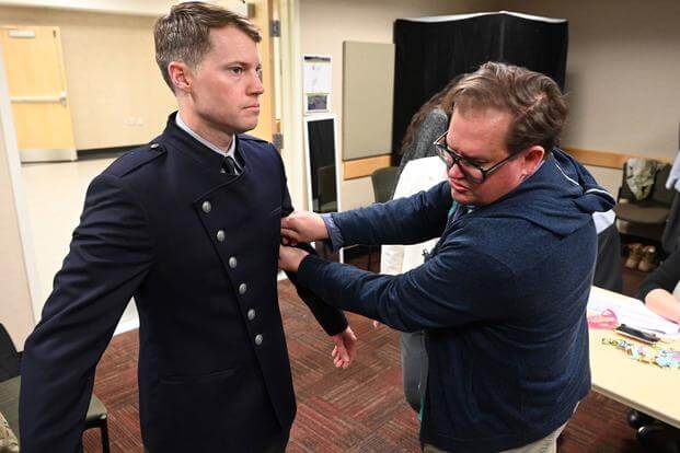 A tailor measures a Space Force members wearing an unmarked prototype of the service's dress uniform.